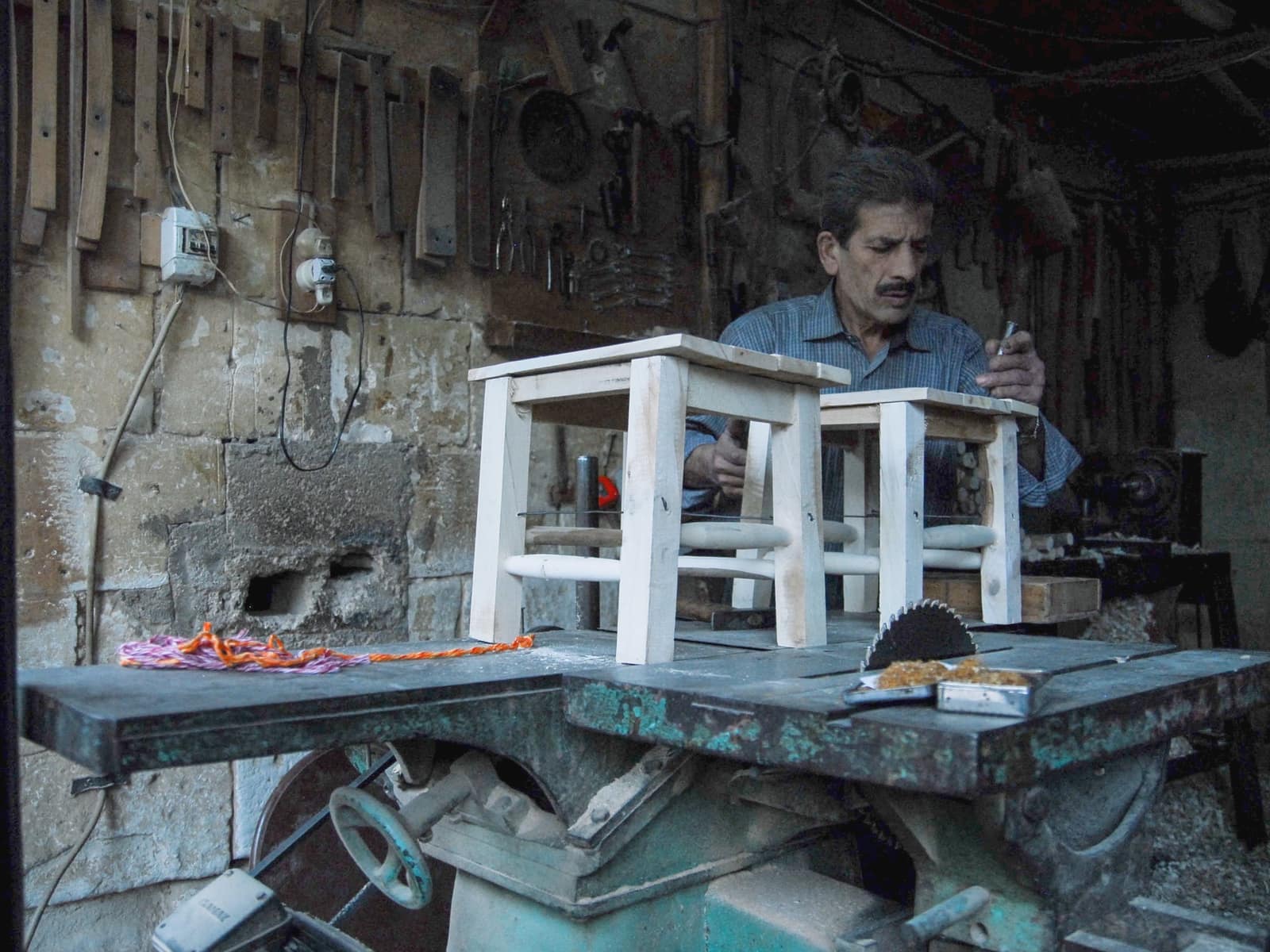A saddle-seat stool at a raised work bench