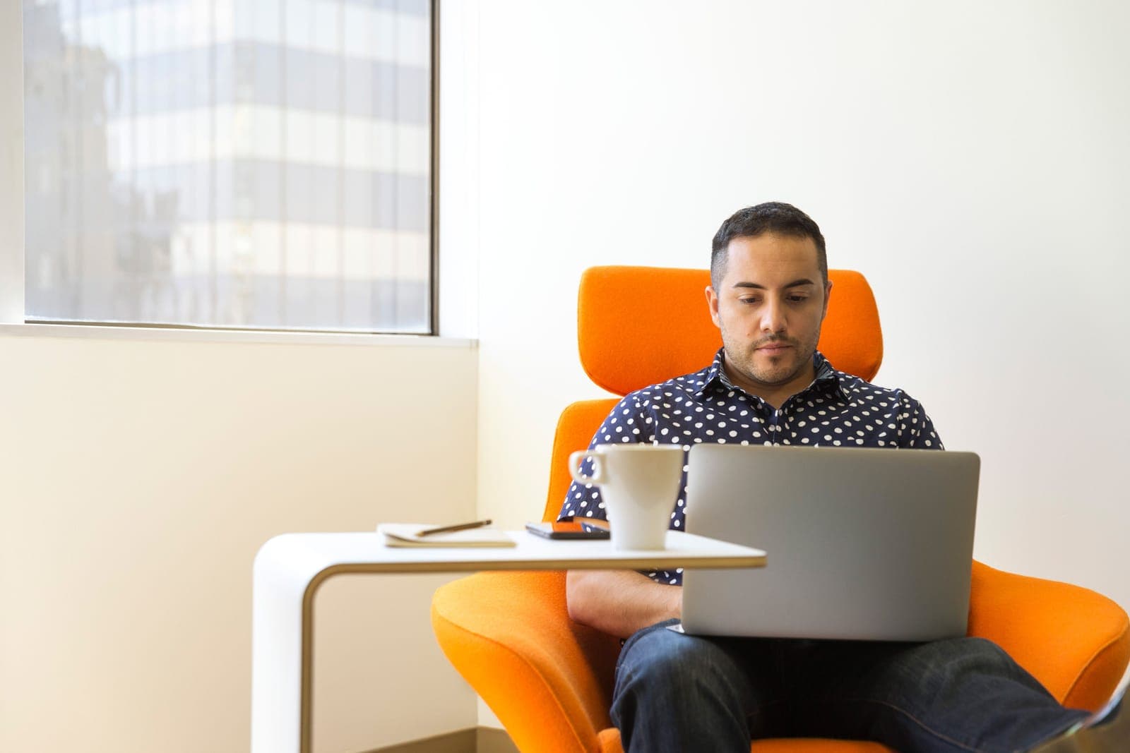 A tall person working at a desk with a laptop