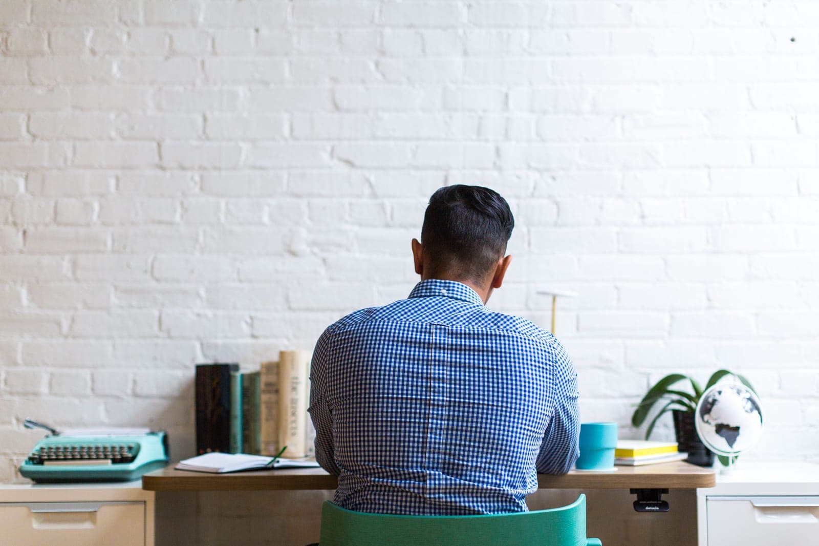Person working at a desk with a hand pressed to their lower back